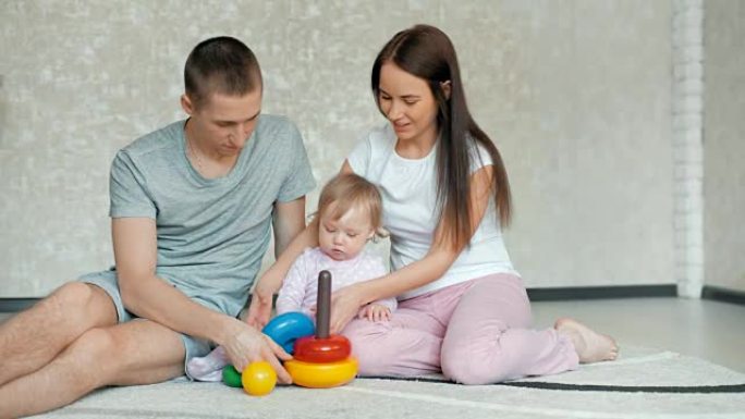 快乐的家庭在家里玩耍。一家人坐在地板上一起玩