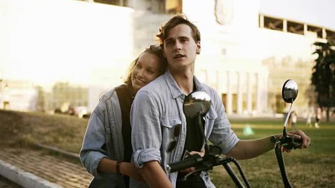 年轻有魅力的夫妇坐在街上的自行车上拥抱和享受。都穿着蓝色衬衫。阳光