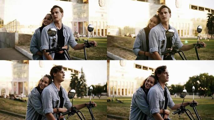 年轻有魅力的夫妇坐在街上的自行车上拥抱和享受。都穿着蓝色衬衫。阳光