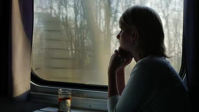 舒适的旅行。一名年轻女子正在火车上旅行，在她旁边的杯架里有一杯茶