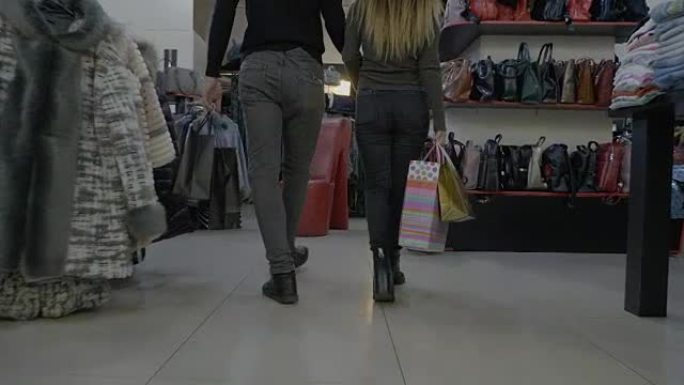迷人的时尚情侣手牵手和购物袋一起在服装店散步
