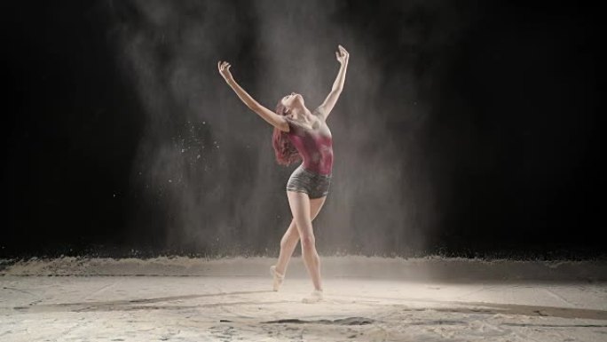 美丽的芭蕾舞演员在演播室与粉雪跳舞。慢动作