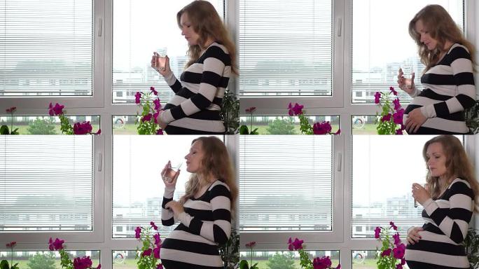 孕妇站在窗前用玻璃喝水