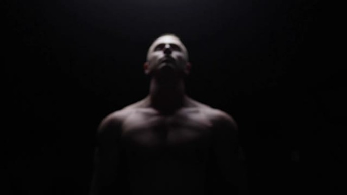 Shirtless bodybuilder posing in dark