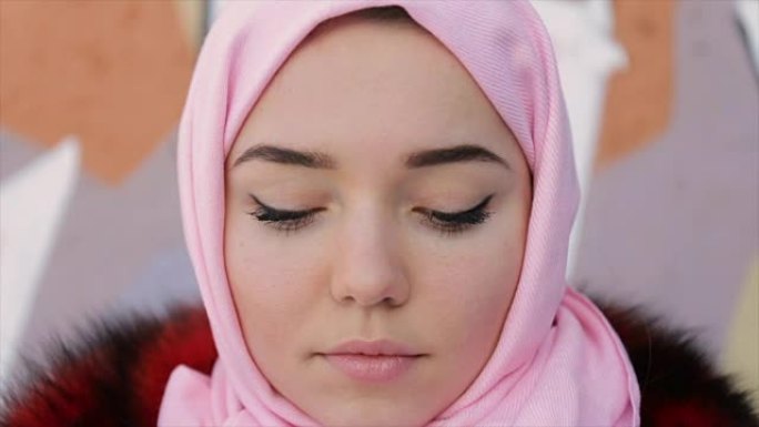 一名穆斯林妇女的肖像，头上戴着围巾，墙壁背景