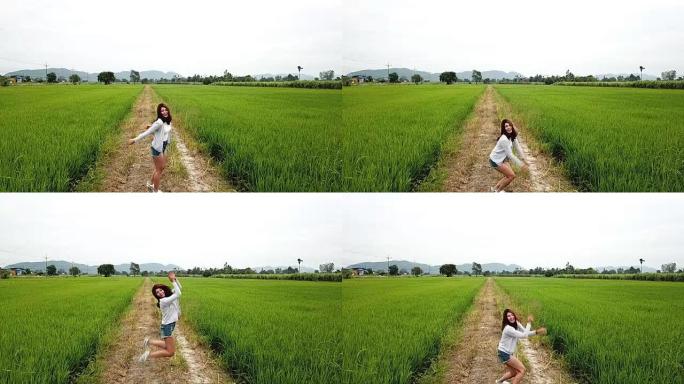 快乐的亚洲女人享受日落时在泰国乡村的绿色稻田