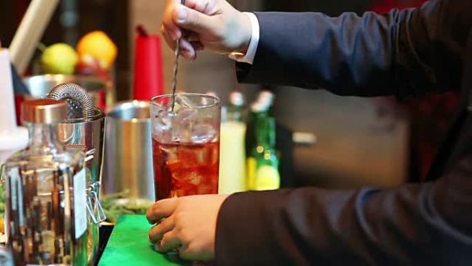 调酒师在酒吧将鸡尾酒与酒杯混合，将酒保手倒入酒杯中