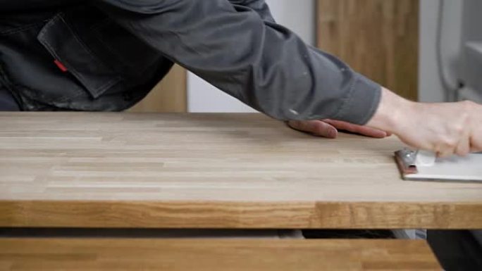 木匠正在加工木板，用砂纸研磨，在表面上摩擦，双手特写