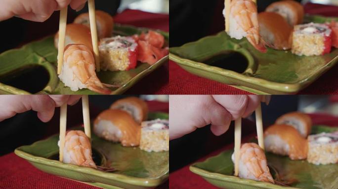 女人在日本餐厅用筷子蘸虾寿司。
