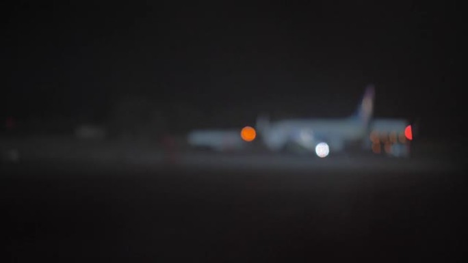 飞机和飞机牵引车在机场的夜景，散焦