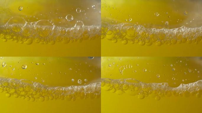 带有橙色饮料的脏瓶的一部分，带有气泡和泡沫。工作室拍摄。特写。