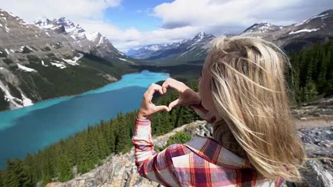 热爱大自然的年轻女子在加拿大山湖上塑造了心形