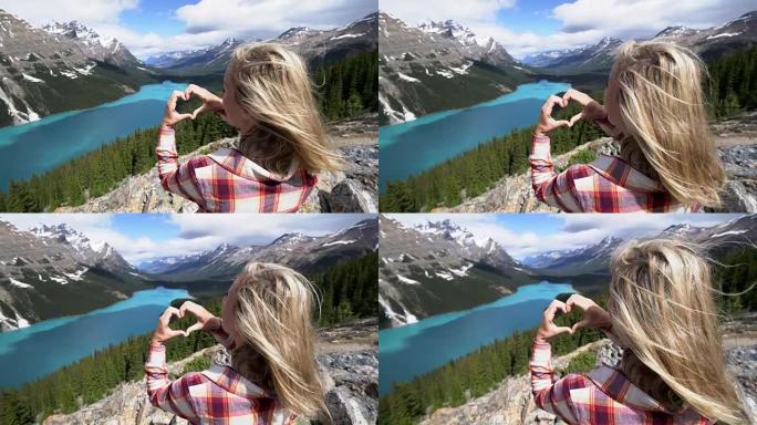 热爱大自然的年轻女子在加拿大山湖上塑造了心形