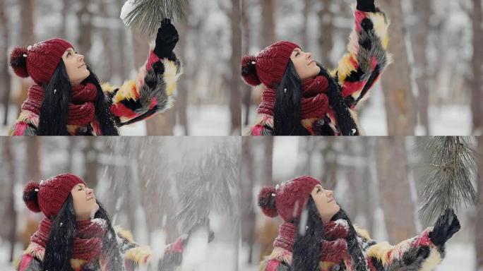 Happy woman sprinkle down snow standing under pine