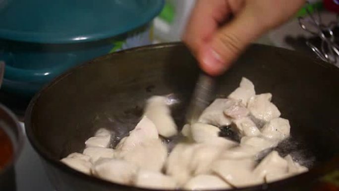 厨师从煎锅上取下盖子，用鸡肉块搅动叉子。
