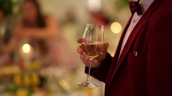 穿着勃艮第燕尾服的绅士，手里拿着一杯白葡萄酒。派对主题。