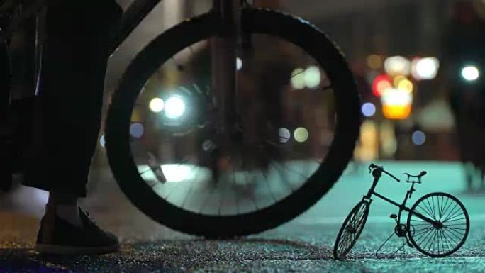 在小规模自行车timalapse模型的背景下，许多骑自行车的人在夜间骑自行车游行中被照明的夜市街道模