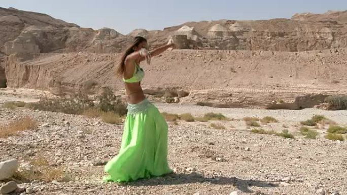 漂亮的女舞者。肚皮舞。沙漠。性感的绿蓝裙舞。长针。