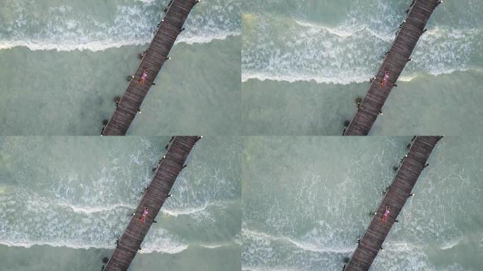 空中: 女孩躺在木桥上。背景上的波浪