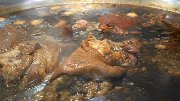猪腿在一个大锅里用一堆草药炖热汤