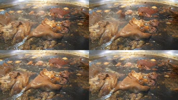 猪腿在一个大锅里用一堆草药炖热汤