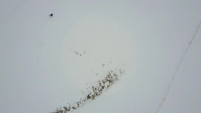 在白雪皑皑的白色斜坡上滑雪的下坡滑雪者的直接头顶