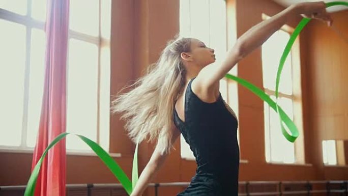 艺术体操-年轻女子用绿丝带慢动作训练体操