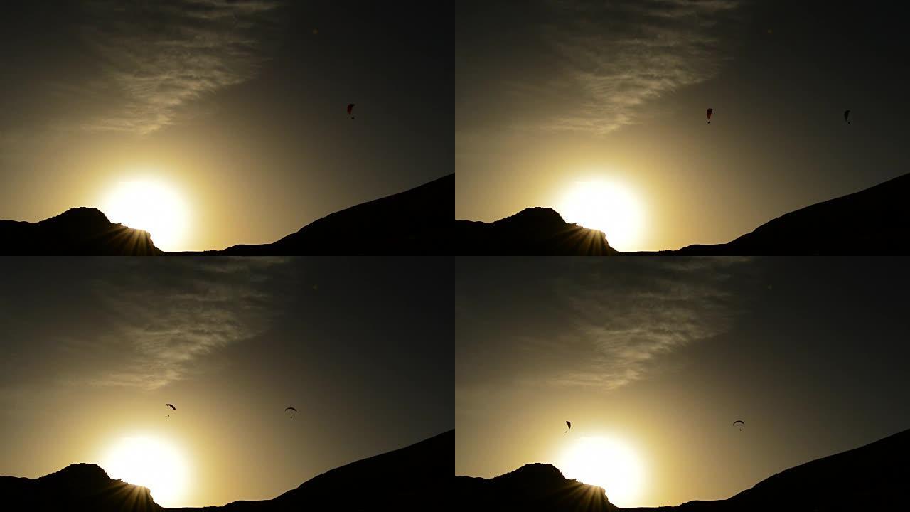 滑翔伞在山上日落时滑翔伞飞行，背光