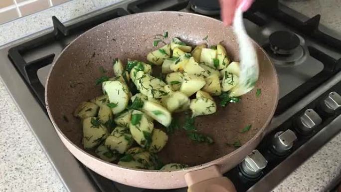 用葱在锅上炸的年轻土豆