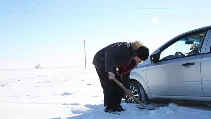 司机用铲子从雪地上挖出汽车。