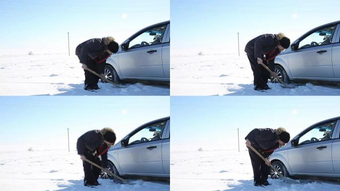 司机用铲子从雪地上挖出汽车。