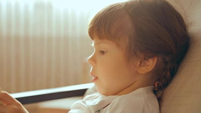 Small girl reading a book in armchair