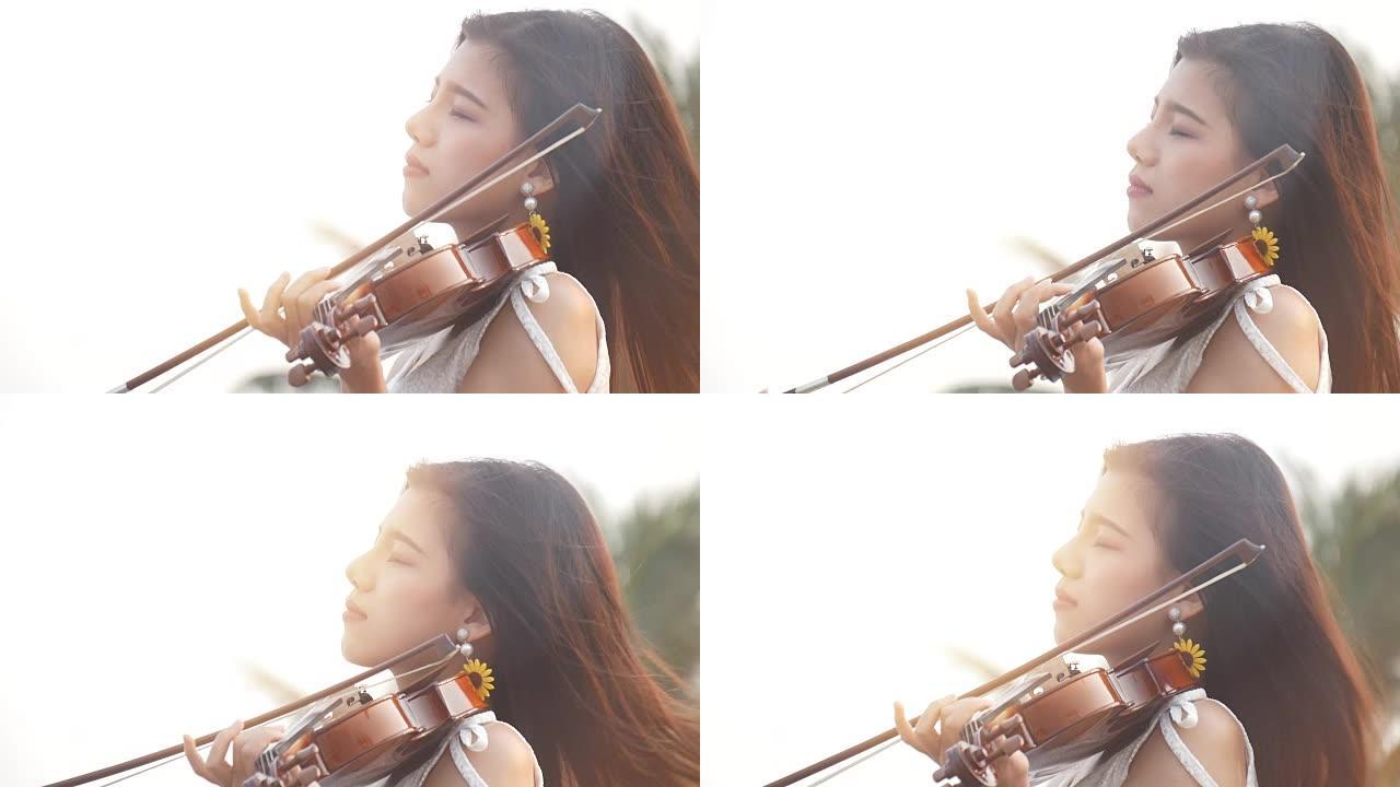 慢动作亚洲女孩在沙滩上拉小提琴，带滤光器。