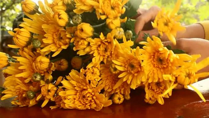 年轻女子花店的手的特写镜头在桌子上创作一束鲜花