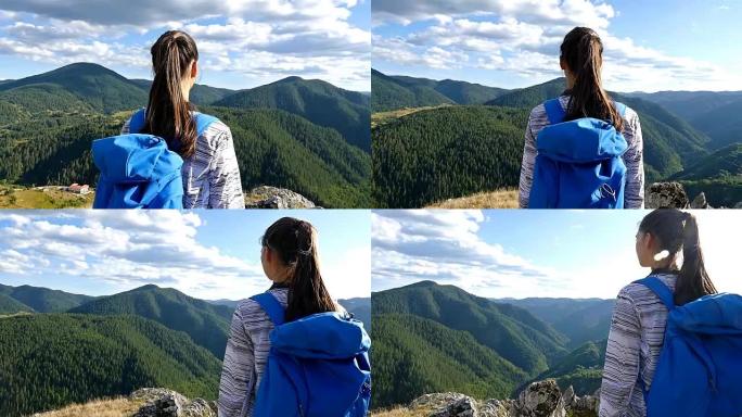 女人背着背包在山顶看日落，徒步女孩庆祝生活，风景优美的自然景观，享受假期旅行冒险