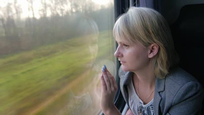 一个穿着西装的女人坐火车，看着窗外