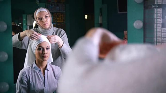 两名穆斯林妇女在镜子前系伊斯兰头巾，准备举行婚礼