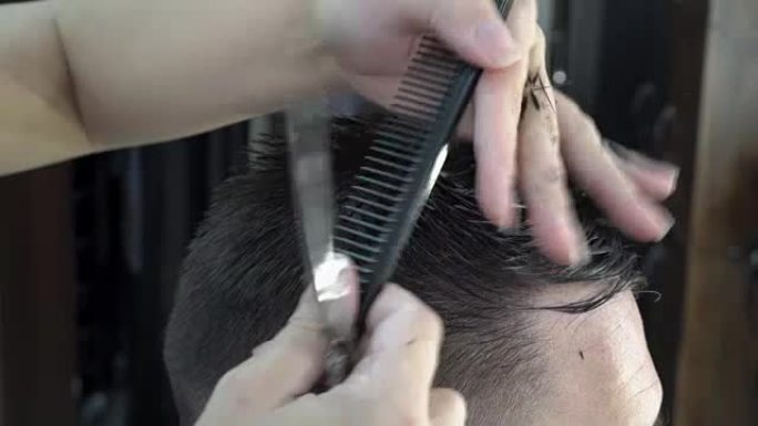 一个在理发店理发的人。理发师剪了他的发梢。特写，高度细节。