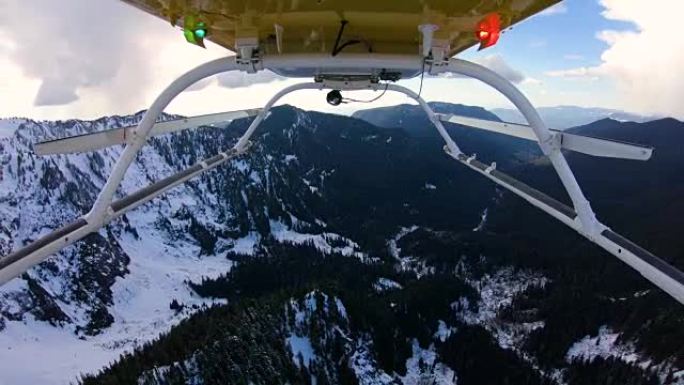 直升机从喀斯喀特山脉以下的冰冷山谷上升到山脊边缘上方飞行