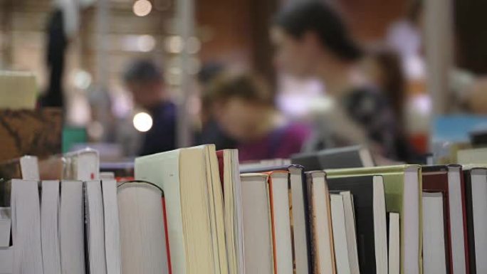 书店的书架上有书堆，年轻人竖起大拇指，看着书。人们看书。学生在书店看书或课本。概念学习和知识。教育，