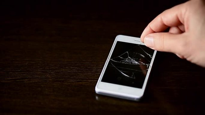 屏幕破裂的智能手机。一名男子试图打开一部坏掉的电话