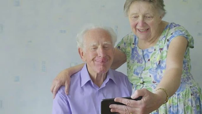 高级夫妇在智能手机上拉滑稽的脸