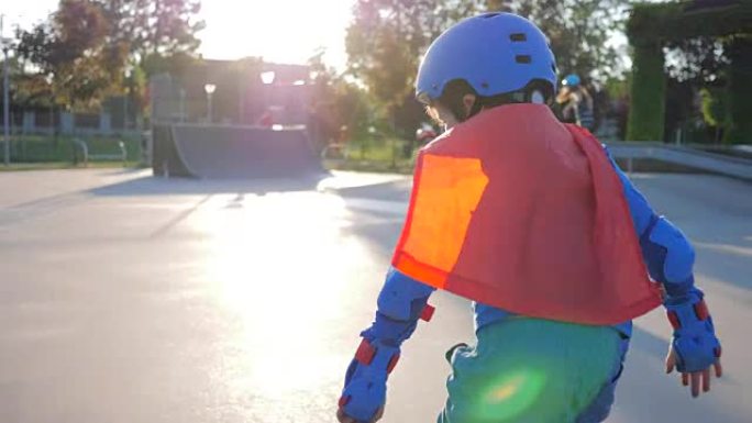 体育活动，穿着超级英雄服装的无所畏惧的孩子在滑板公园骑着滚轮并挥舞双手