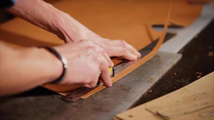 皮革工匠用刀切割产品的边缘，使其均匀