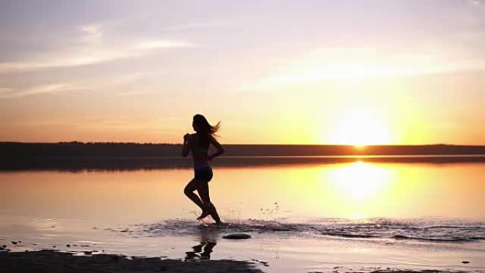 长头发的苗条女人在户外奔跑。在水边慢跑。海边。阳光照在背景上