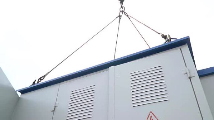 悬挂在建筑起重机上的空气中旋转的变压器箱的底视图