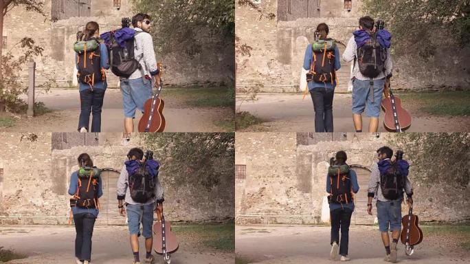 快乐的年轻夫妇背包客游客在日出时带着吉他和睡袋慢动作steadycam走向罗马帕尔科德格里阿奎多蒂公