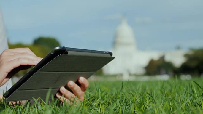 在国会大厦的背景上使用平板电脑，在框架中你只能看到手。美国各地的旅游、学习和旅行概念