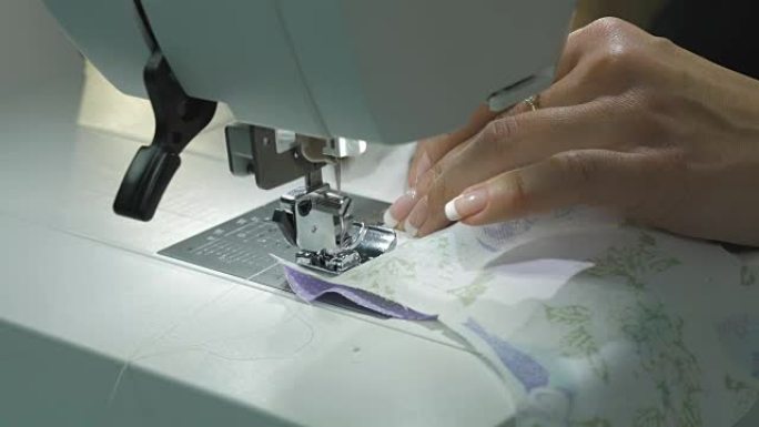 缝纫机缝制两种织物。特写。女性双手控制操作。