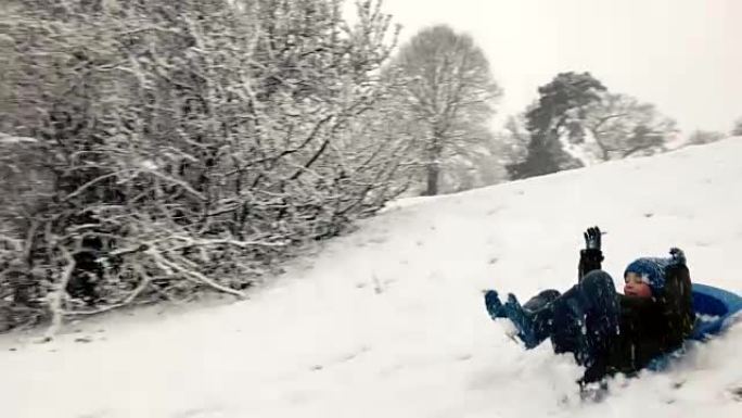 小男孩在雪山上享受雪橇骑行